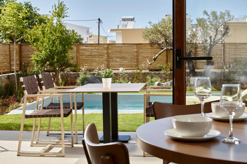 View from the dining table across the garden to the private pool and olive trees at Volta in Gouves, Crete